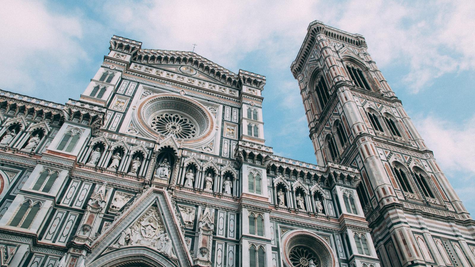 Die Kathedrale von Florenz von unten Fotografiert vor einem leicht bewölkten blauen Himmel.