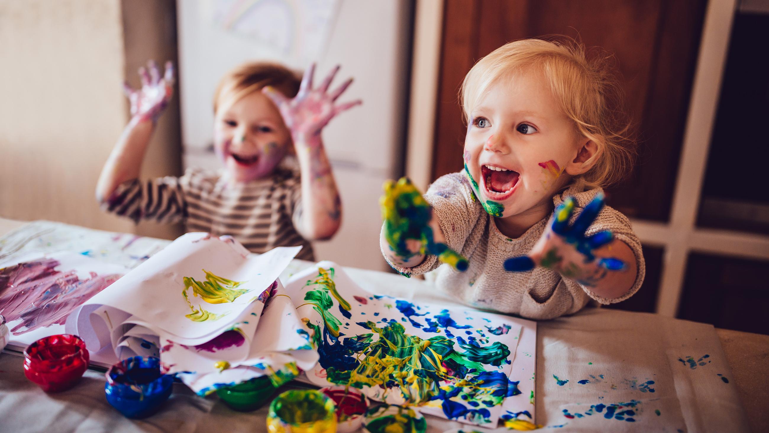 Zwei fröhliche Kinder beim Malen mit Fingerfarben