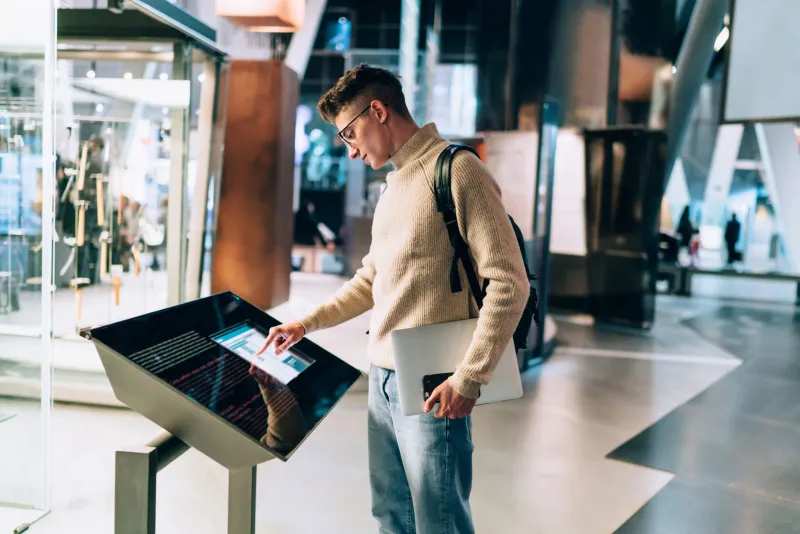 Mann in Museum tippt auf Touchscreen