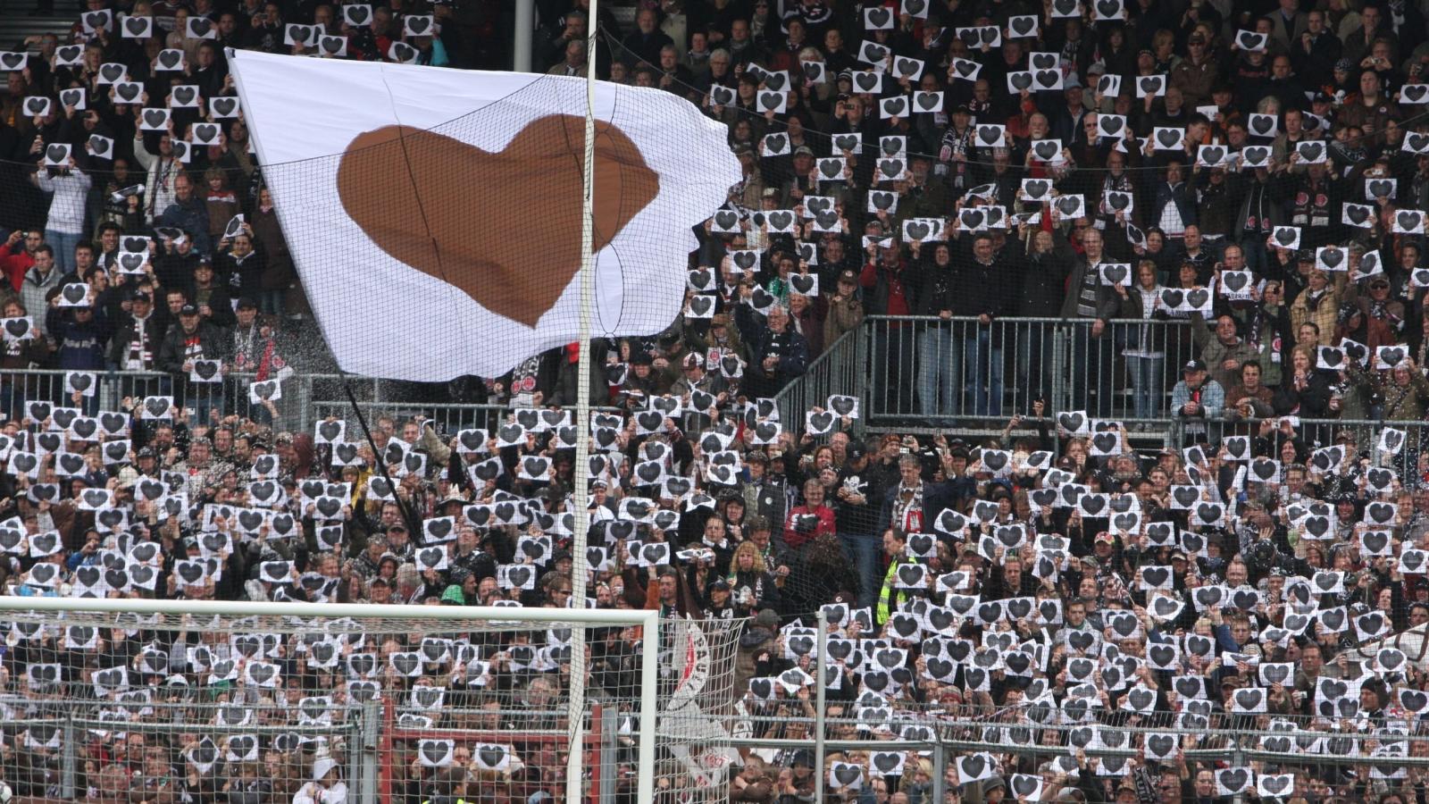 Foto einer Menschenmasse in einem Stadion, die Bilder von Herzen hochhalten