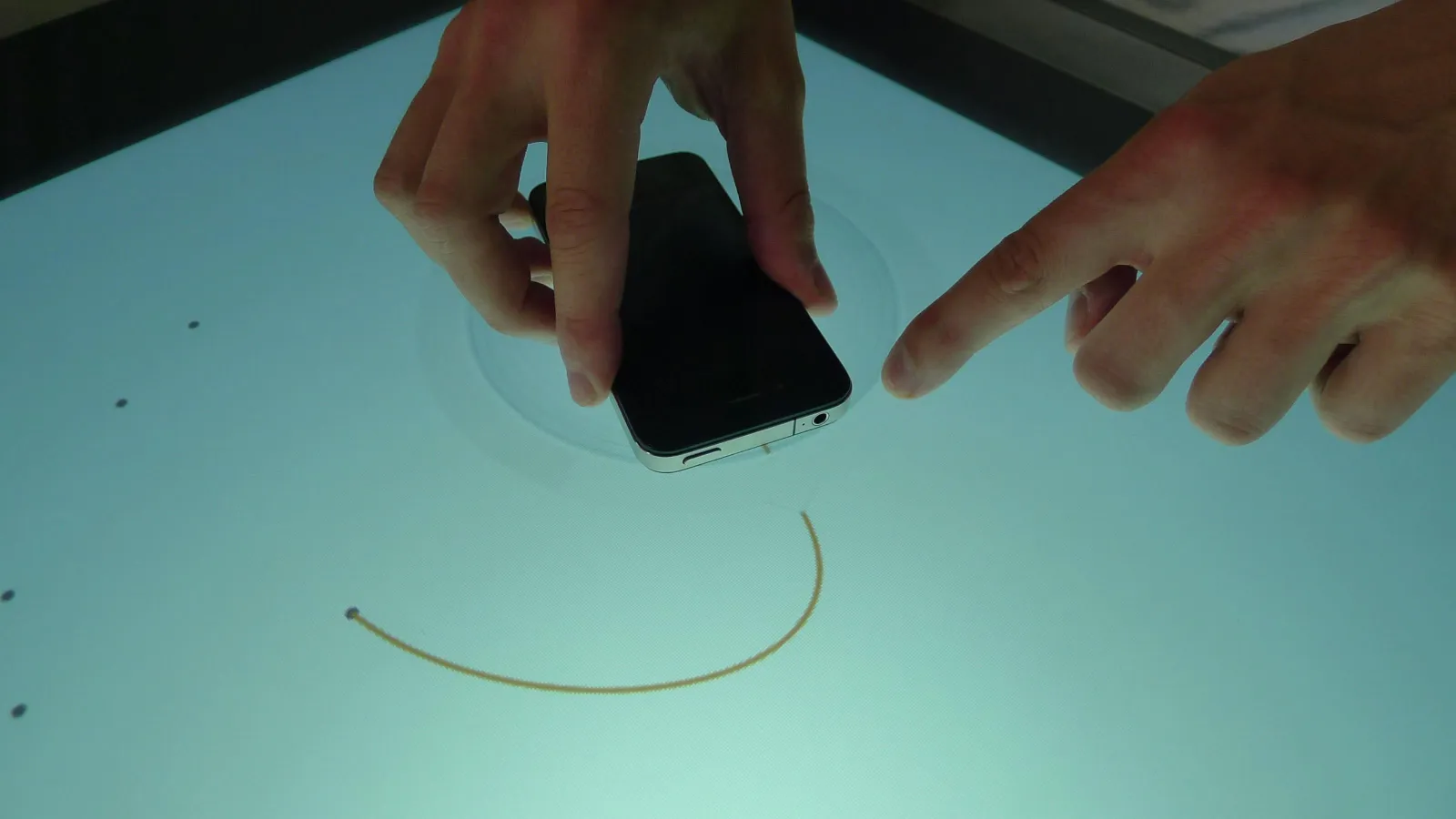 Mithilfe eines Prototyps zeigt eine Person, wie die Anwendung mittels Smartphone erfolgen soll und wie die Funktionsweise des Multitouch-Tisches ist.
