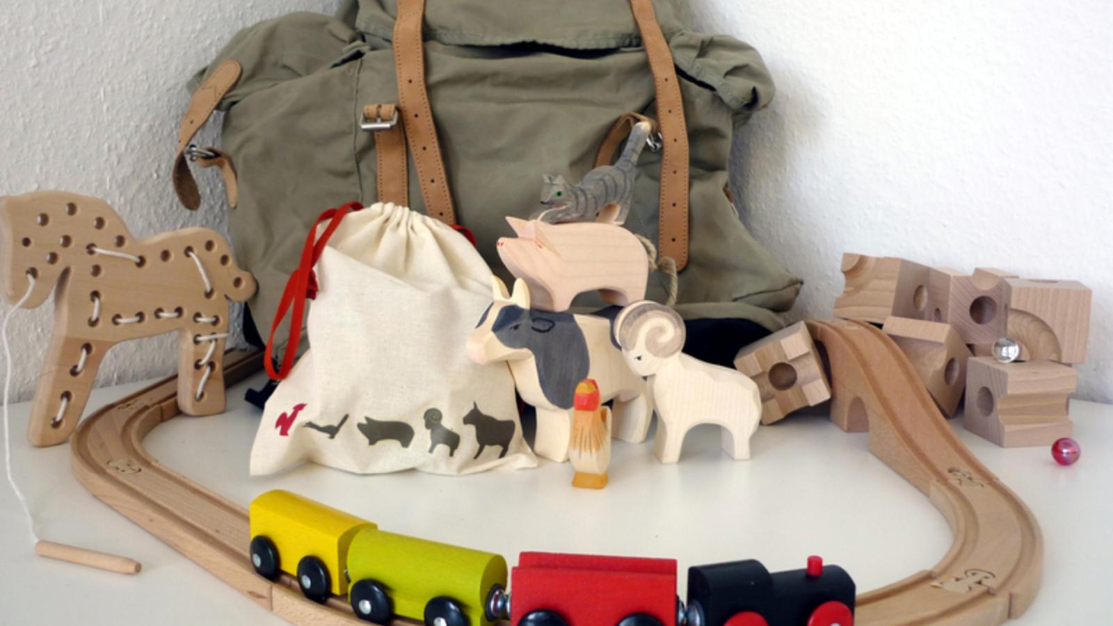 Schienen und Zug einer Spielzeugeisenbahn aus Holz,dazwischen liegt ein Kinderrucksack als mobiles Kinderzimmer der FH Potsdam