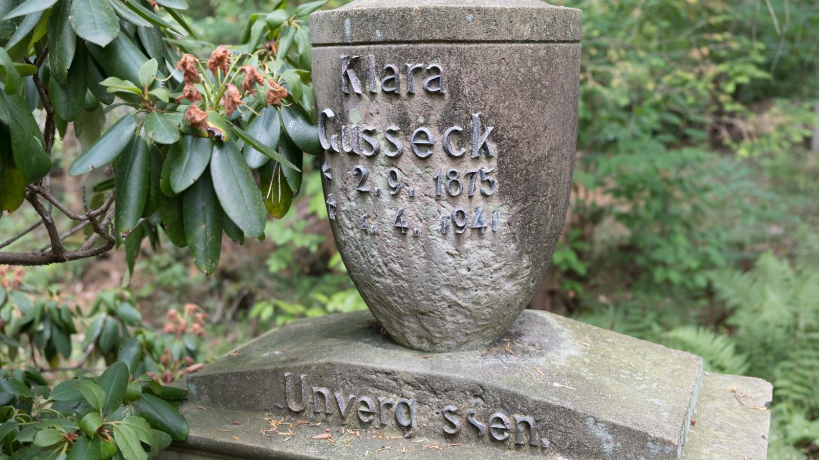 Grabmal von Clara Gusseck mit einer Aufschrift aus kupfernen Lettern. Die Aufschrift umfasst ihren Namen, Geburts- und Sterbedatum und den Zusatz "unvergessen". Clara Gusseck lebte von 1875 bis 1941.