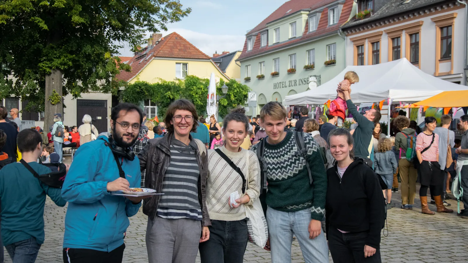 Fünf Teilnehmende stehen in einer Reihe auf einem Platz
