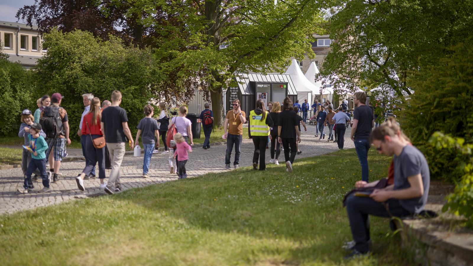 Menschen bewegen sich auf das FHP Mobil beim Potsdamer Tag der Wissenschaften zu