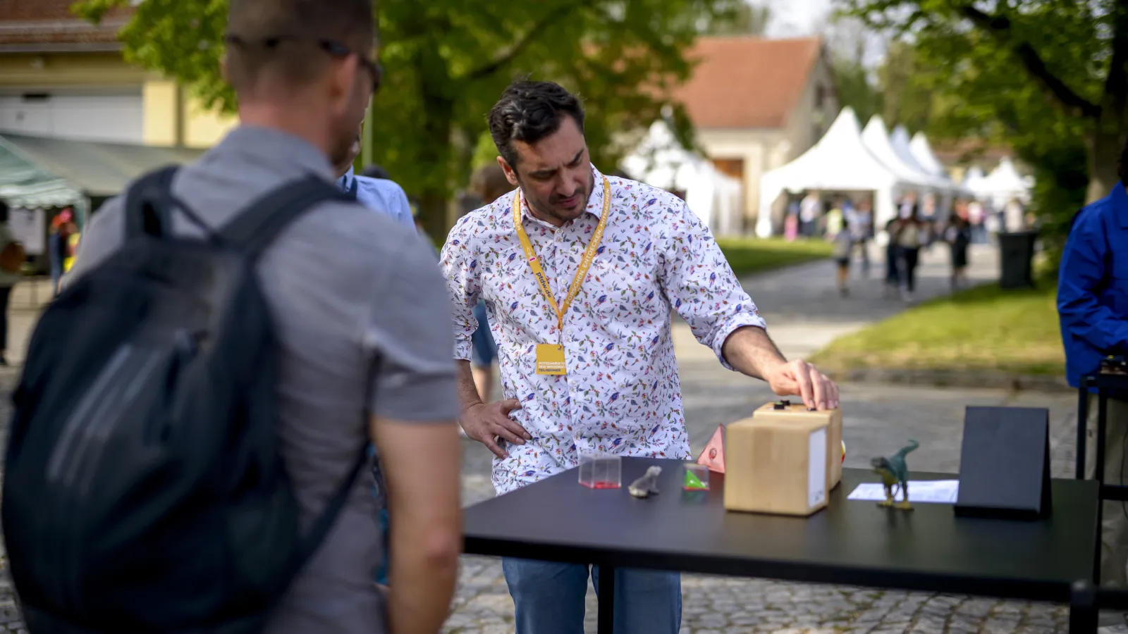 Dr. Alexander Scheidt zeigt einem Jungen und dessen Vater sein preisgekröntes KI-Lernspielzeug beim Potsdamer Tag der Wissenschaften 2022