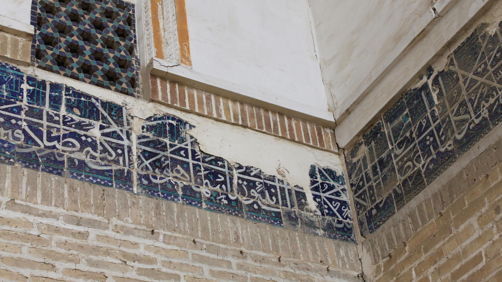 Das Bild zeigt ein beschädigtes Keramikfried an einer Wand in der Kukaldosh Medrese in Buchara.