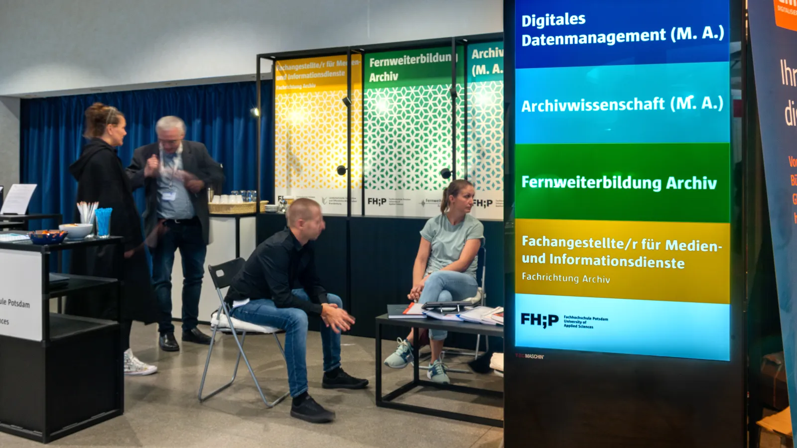 Die Mitarbeitenden der Fachhochschule Potsdam besprechen sich auf dem Messestand der Fernweiterbildung Archiv kurz vor dem Start der Messe