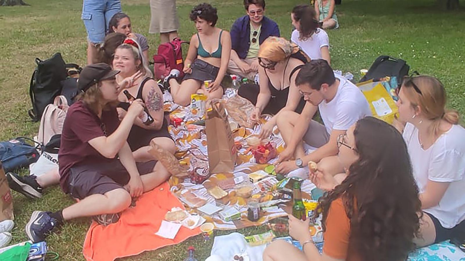 Eine Gruppe Menschen sitzt auf Picknickdecken in der Sonne