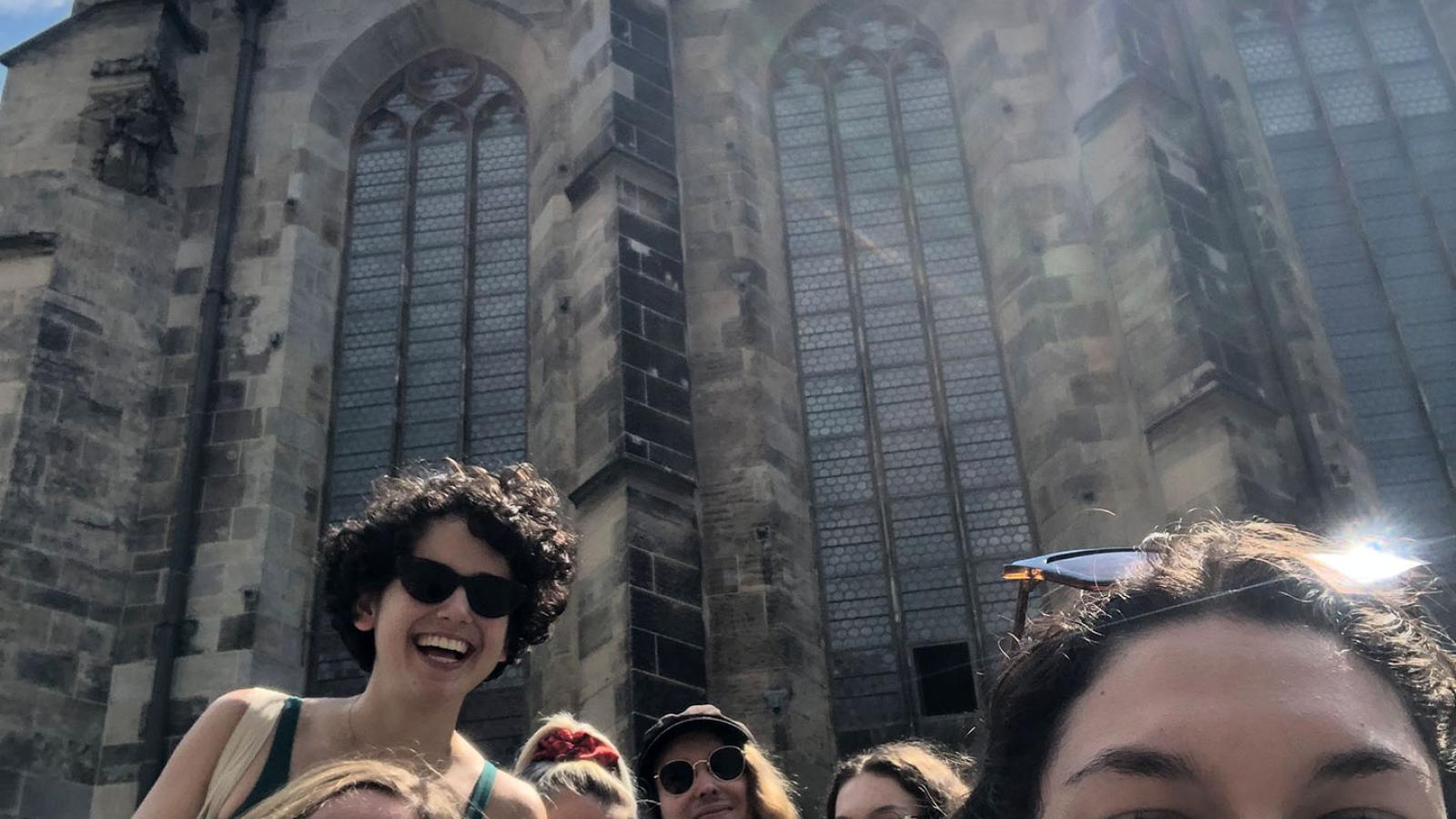 Sechs Personen fotografieren ein Selfie vor einer Kirche in Leipzig. Sie lachen groß.