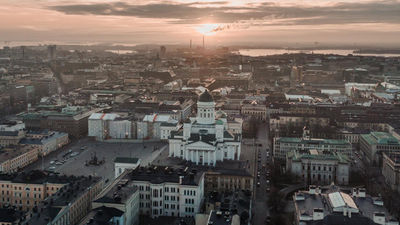 Die Sonnenuntergangs-Sonne wirft durch die Wolken ein letztes Licht auf die Stadt Helsinki von oben. 