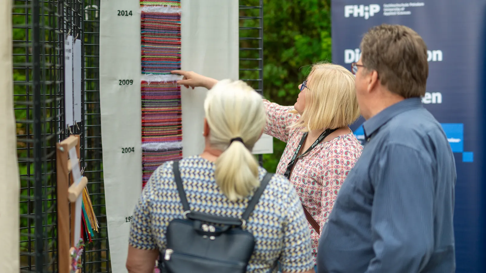 Steffi Brune von der Fachhochschule Potsdam erklärt zwei Besucher*innen die Interface Design Arbeit "Blaue Realitäten"