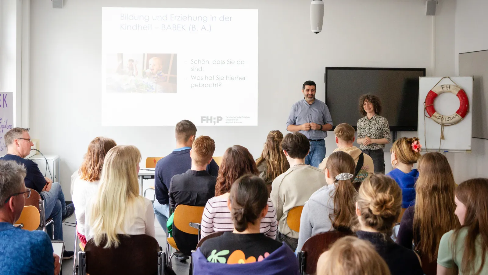 Zwei Dozierende vor einem voll besetzten Seminarraum