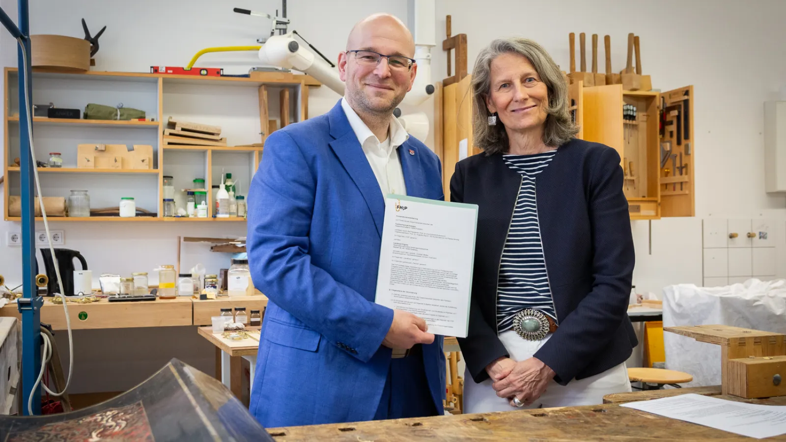 Mann und Frau stehen nebeneinander und halten ein Papier hoch
