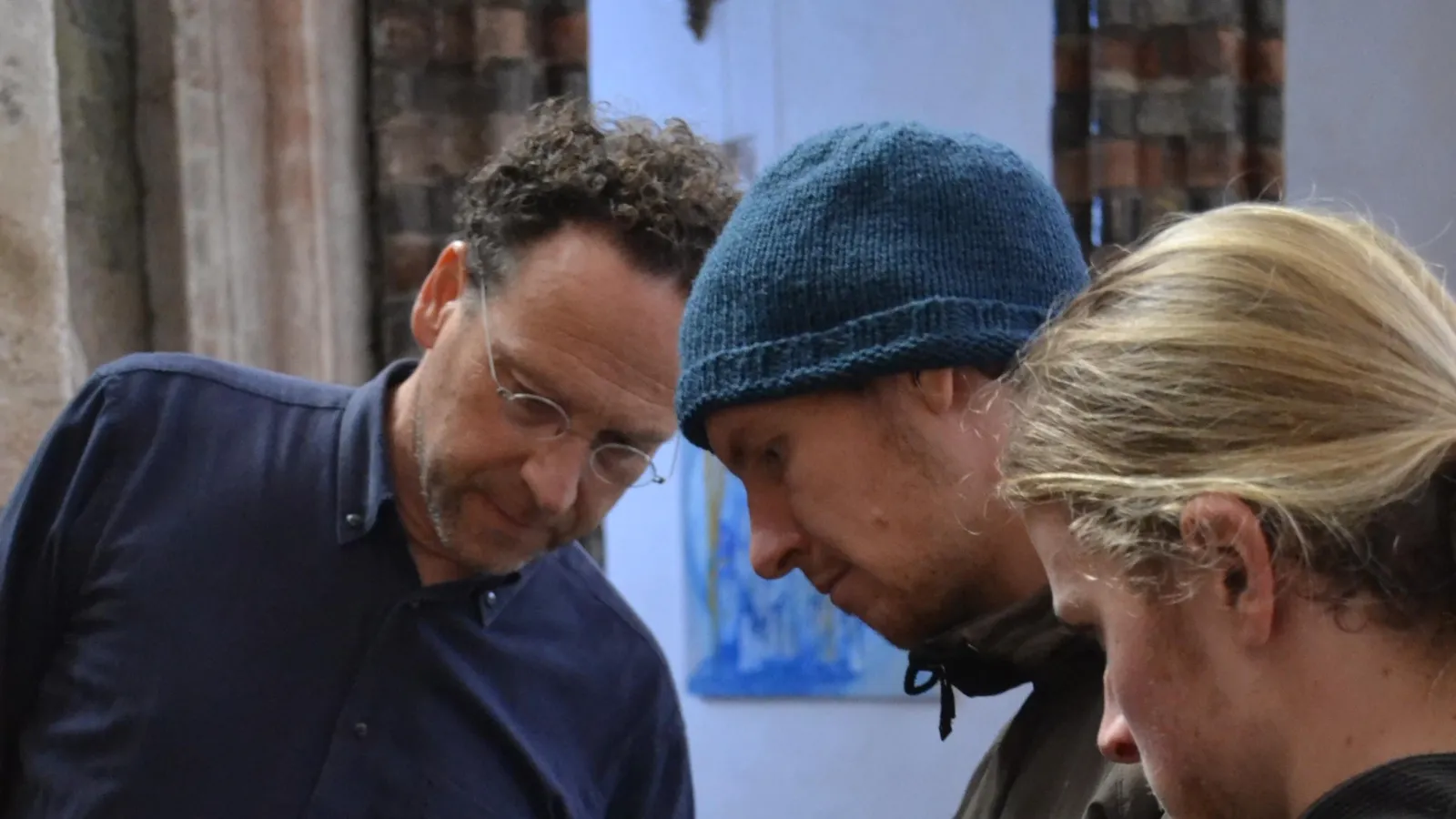 3 Personen über alte Holztür gebeugt