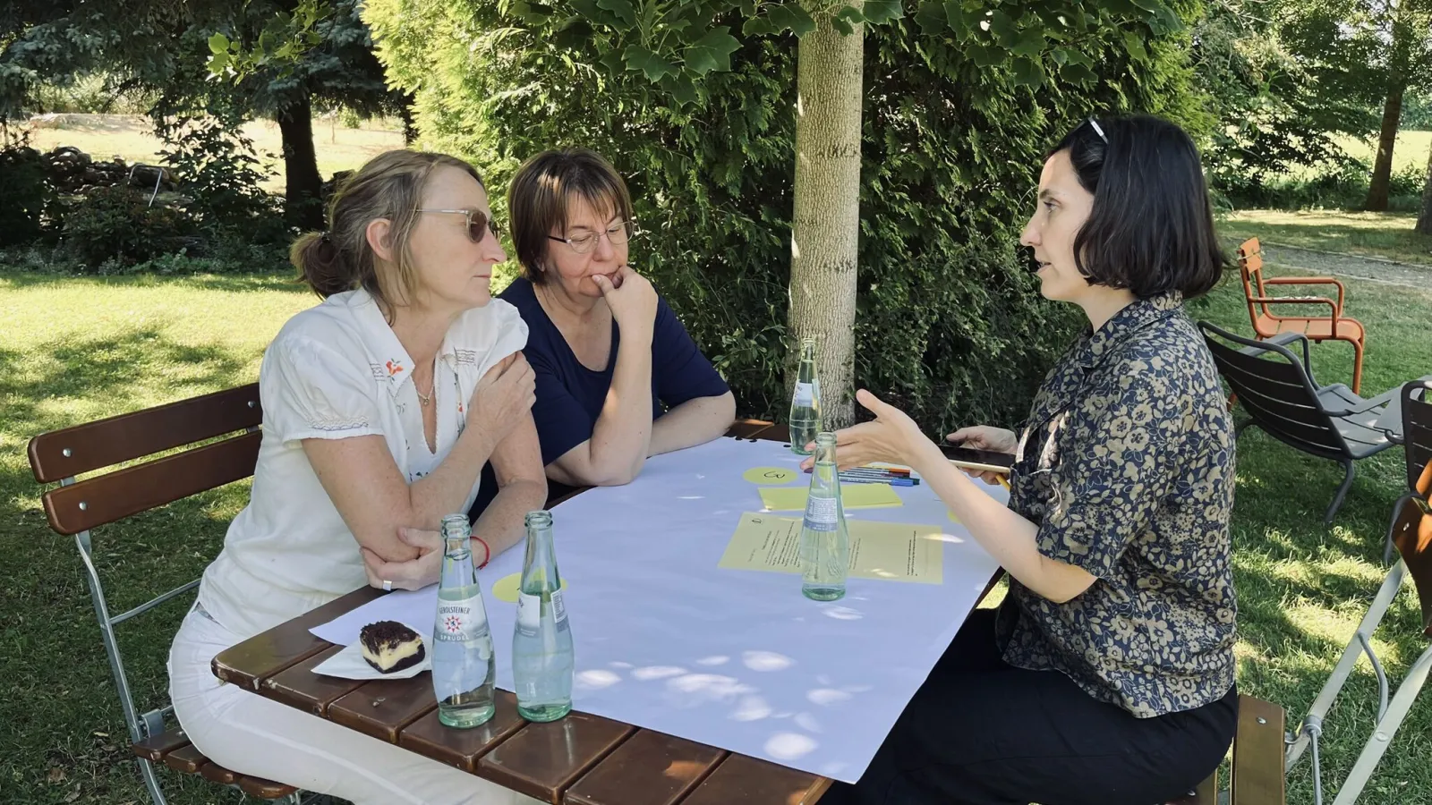 Drei Mitarbeiterinnen besprechen sich draußen am Tisch