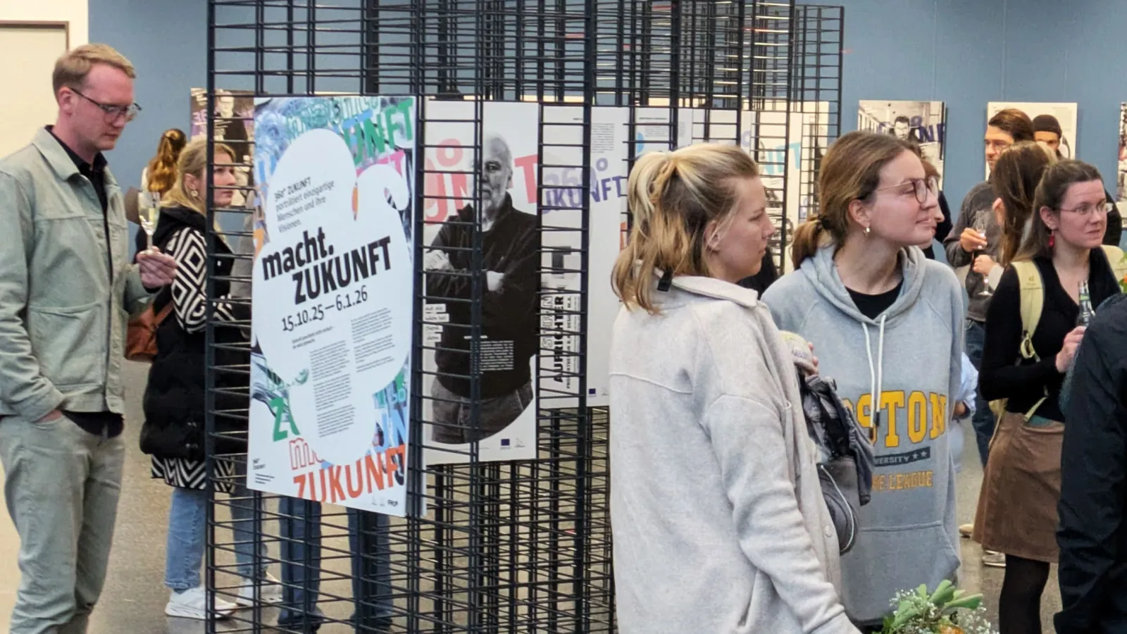 Menschengruppe vor Gitterwand