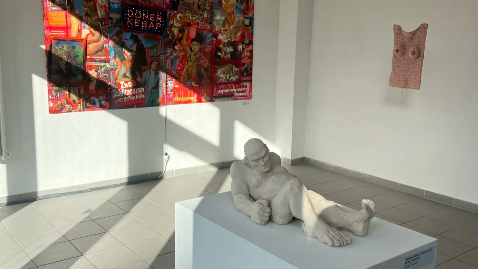 Das Bild zeigt eine Ausstellung mit einer liegenden Skulptur.