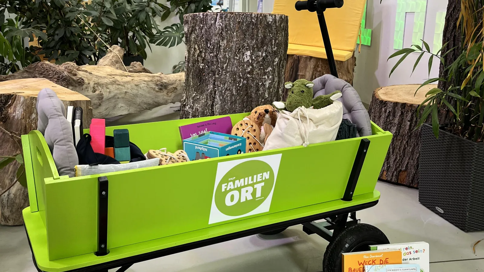 Grüner Bollerwagen gefüllt mit unterschiedlichen Spielmaterialien.