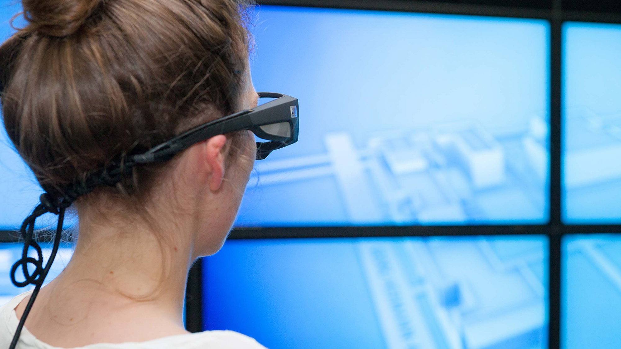 Eine Studentin schaut durch eine Brille auf blaue Bildschirme