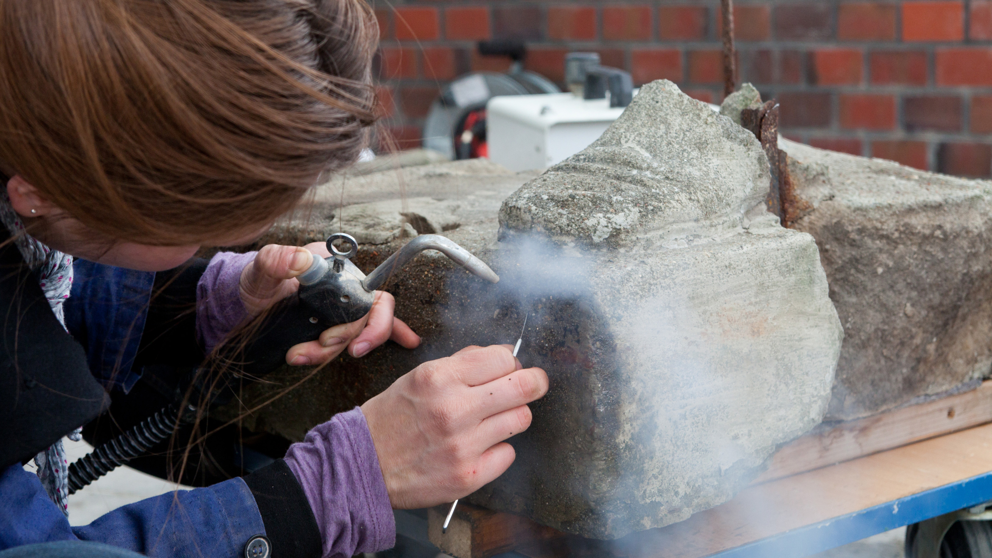 Ein*e Studierende*r arbeitet mit Stein auf dem Campus der FH Potsdam