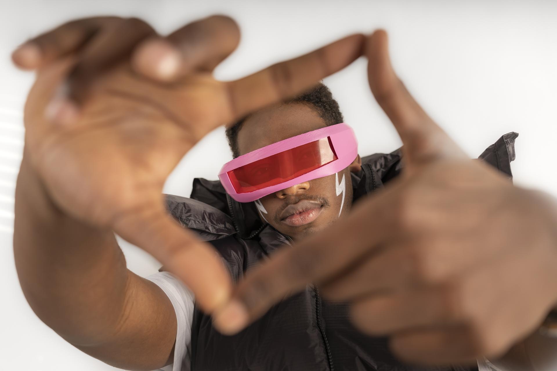 Studierender mit futuristischer Brille formt einen Rahmen mit seinen Händen