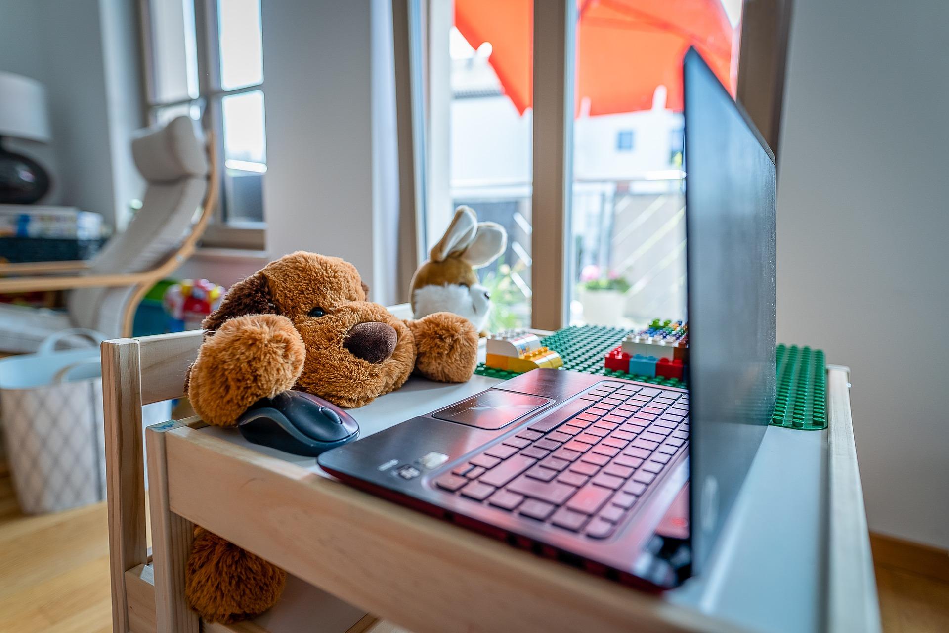 Wohnraum mit Laptop auf Kindertisch und Kuscheltieren