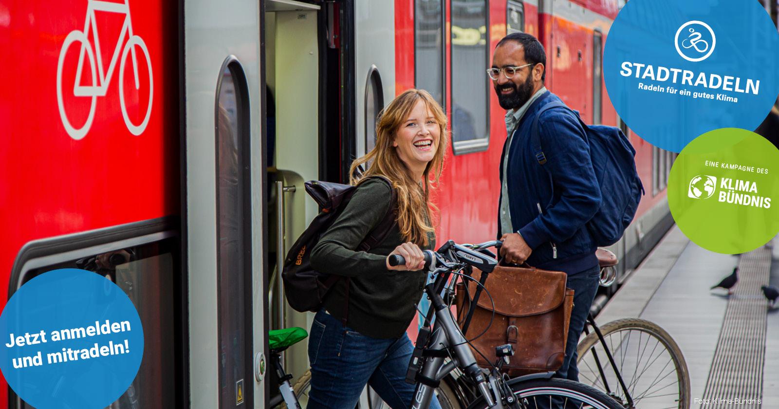 Zwei gut gelaunte Personen mit Fahrrädern vor den geöffneten Türen eines Regionalzuges