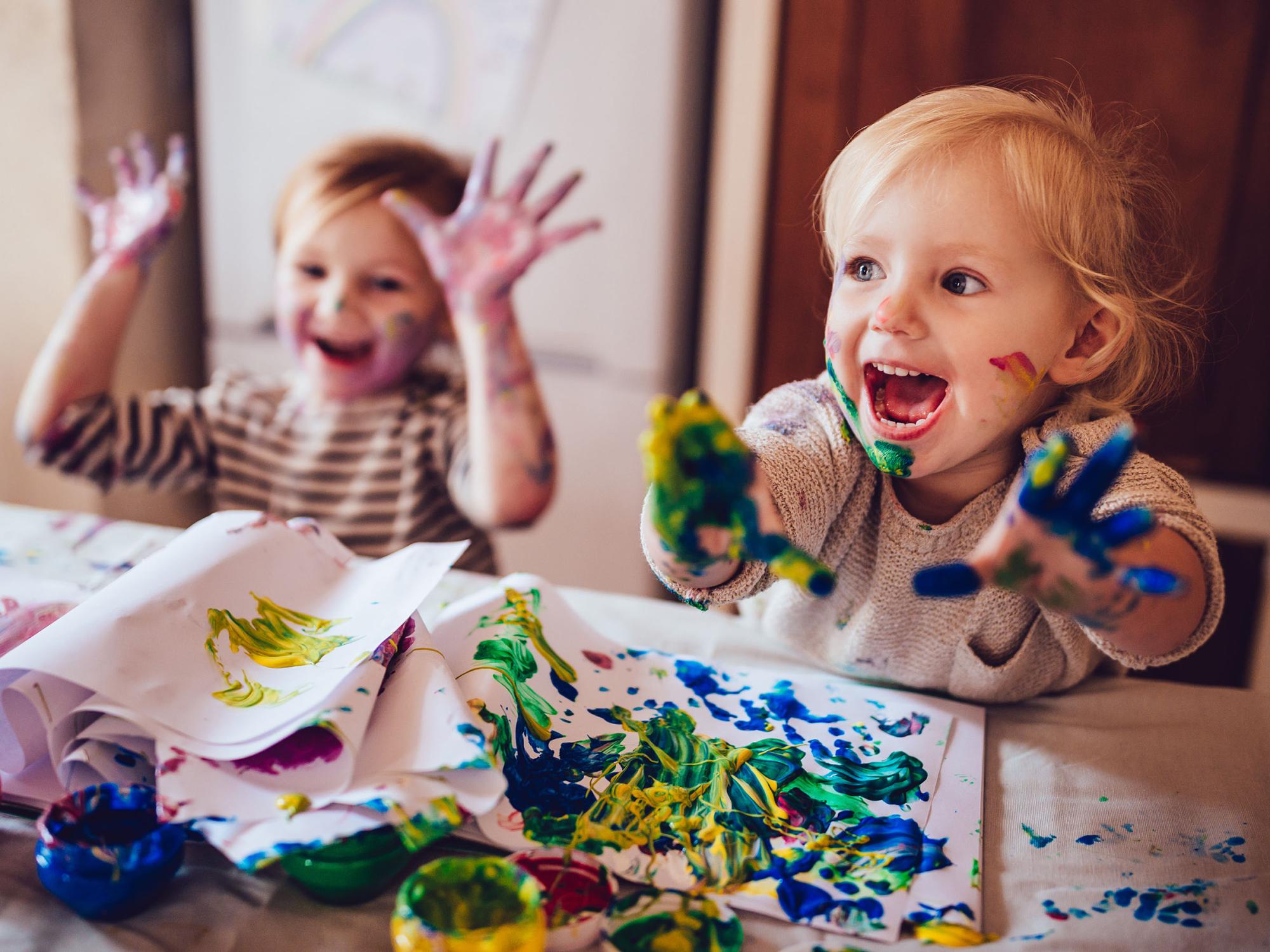Zwei fröhliche Kinder beim Malen mit Fingerfarben