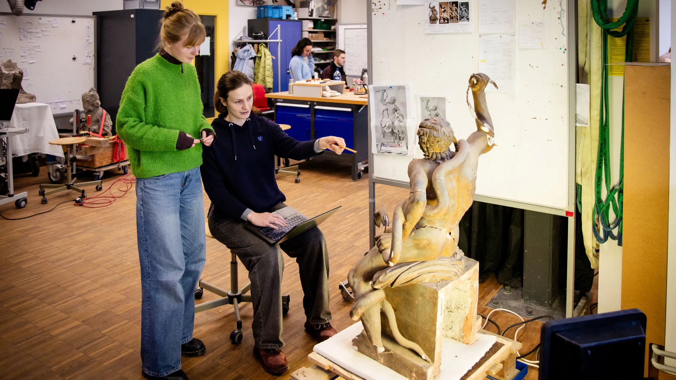 Zwei Studierende vor einer Steinskulptur in der Steinwerkstatt