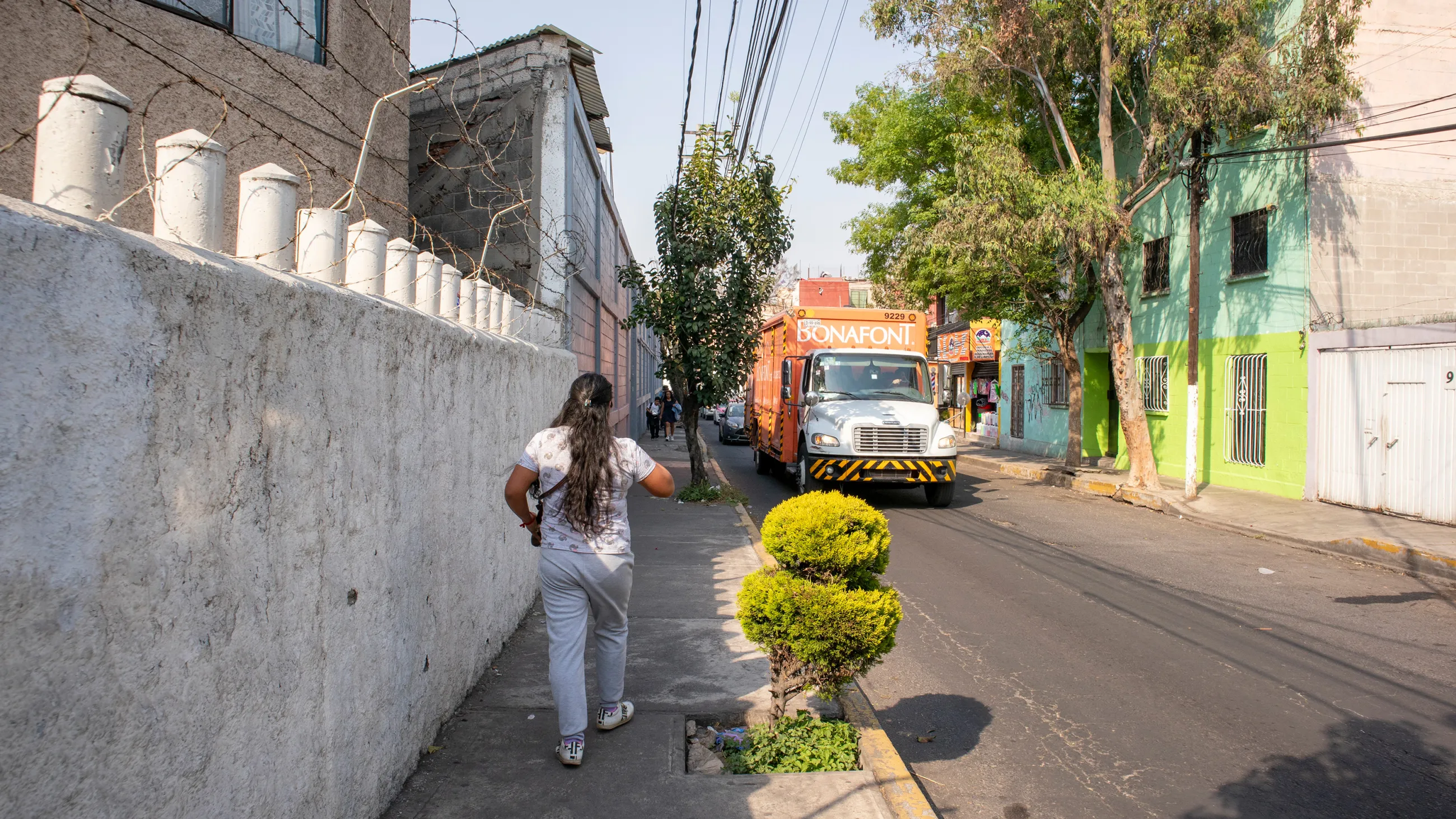 Eine Person läuft einen Gehweg an einer befahrenen Straße entlang.