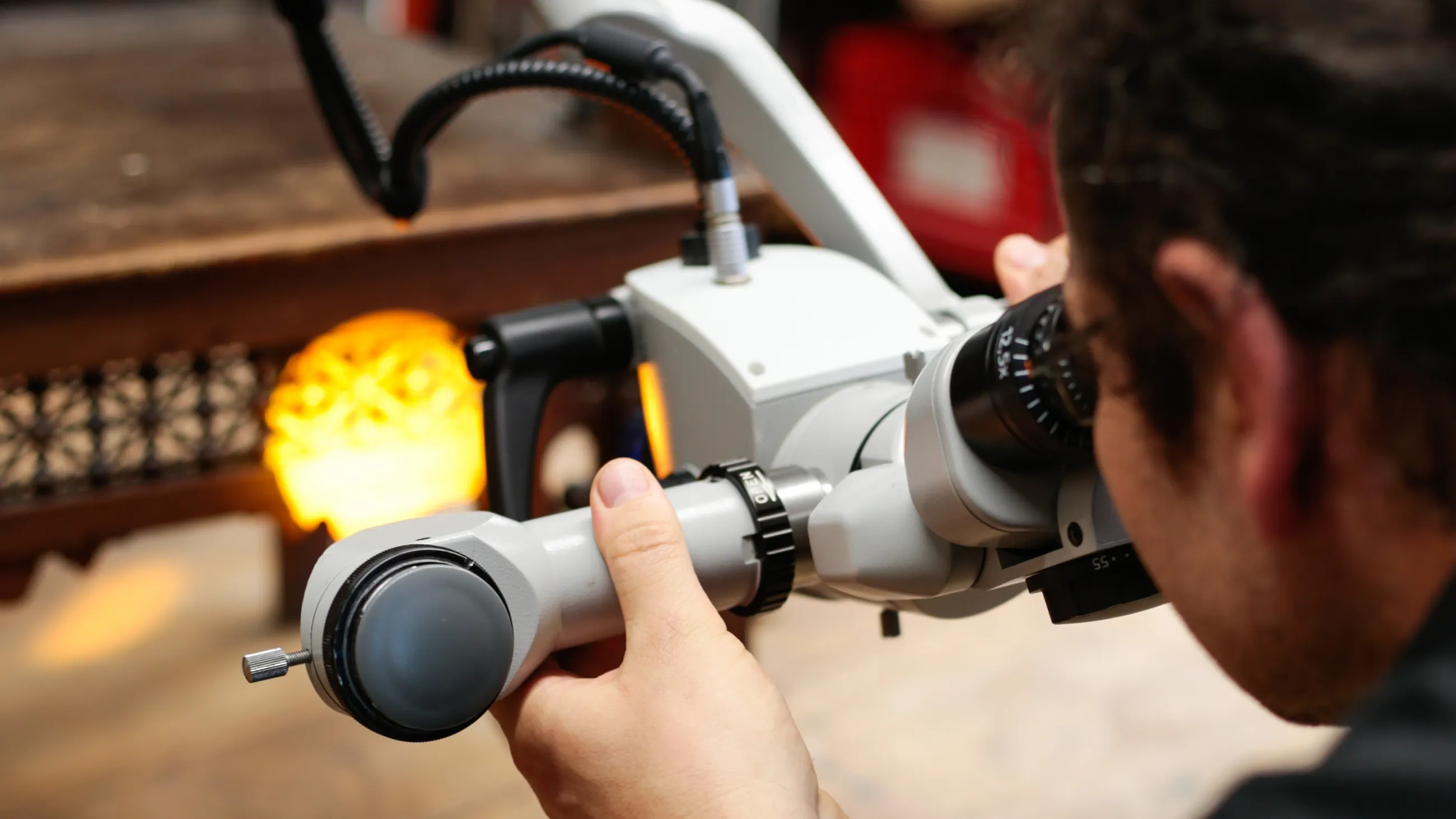 Eine Person schaut sich durch ein Mikroskop einen Holzstuhl an.