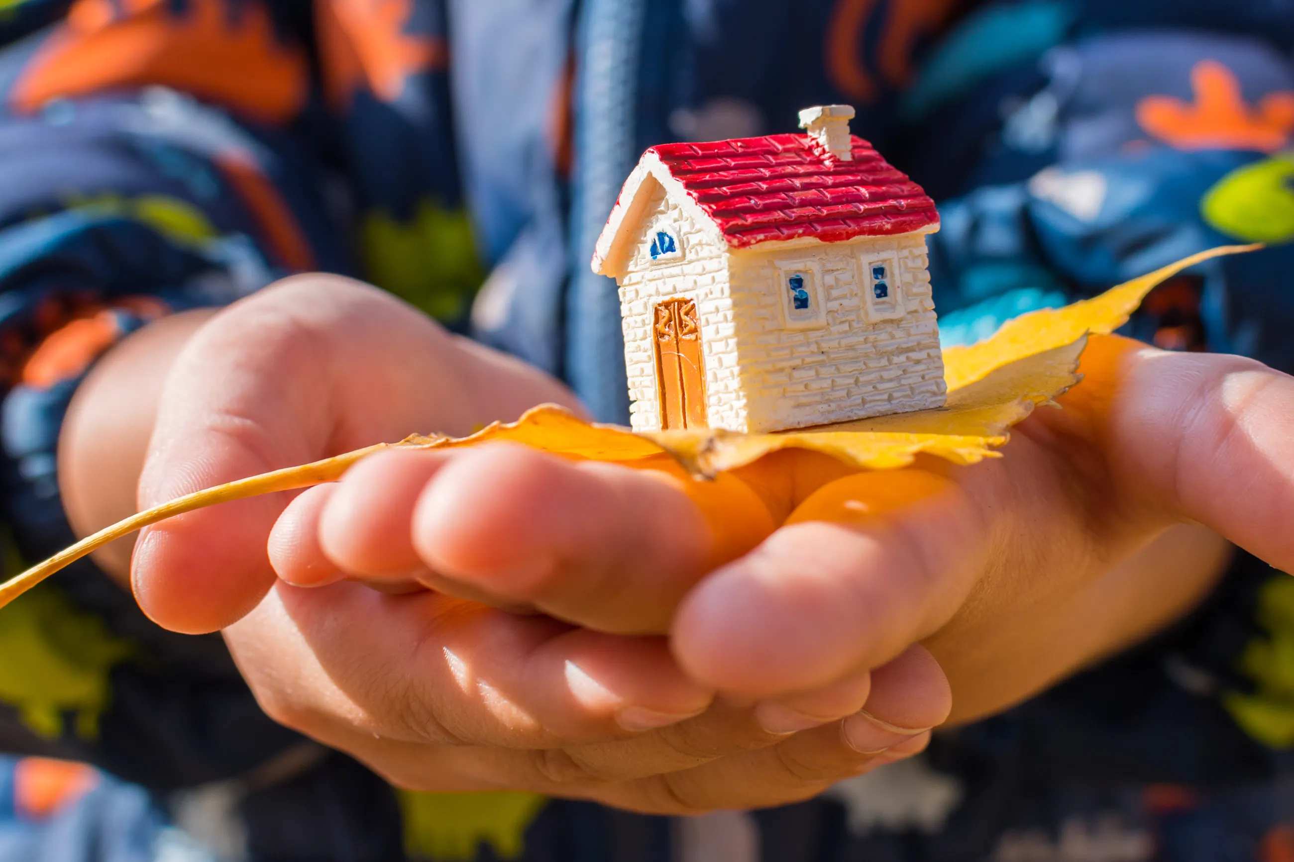 Zwei übereinander gelegte Kinderhände präsentieren ein Modellhaus