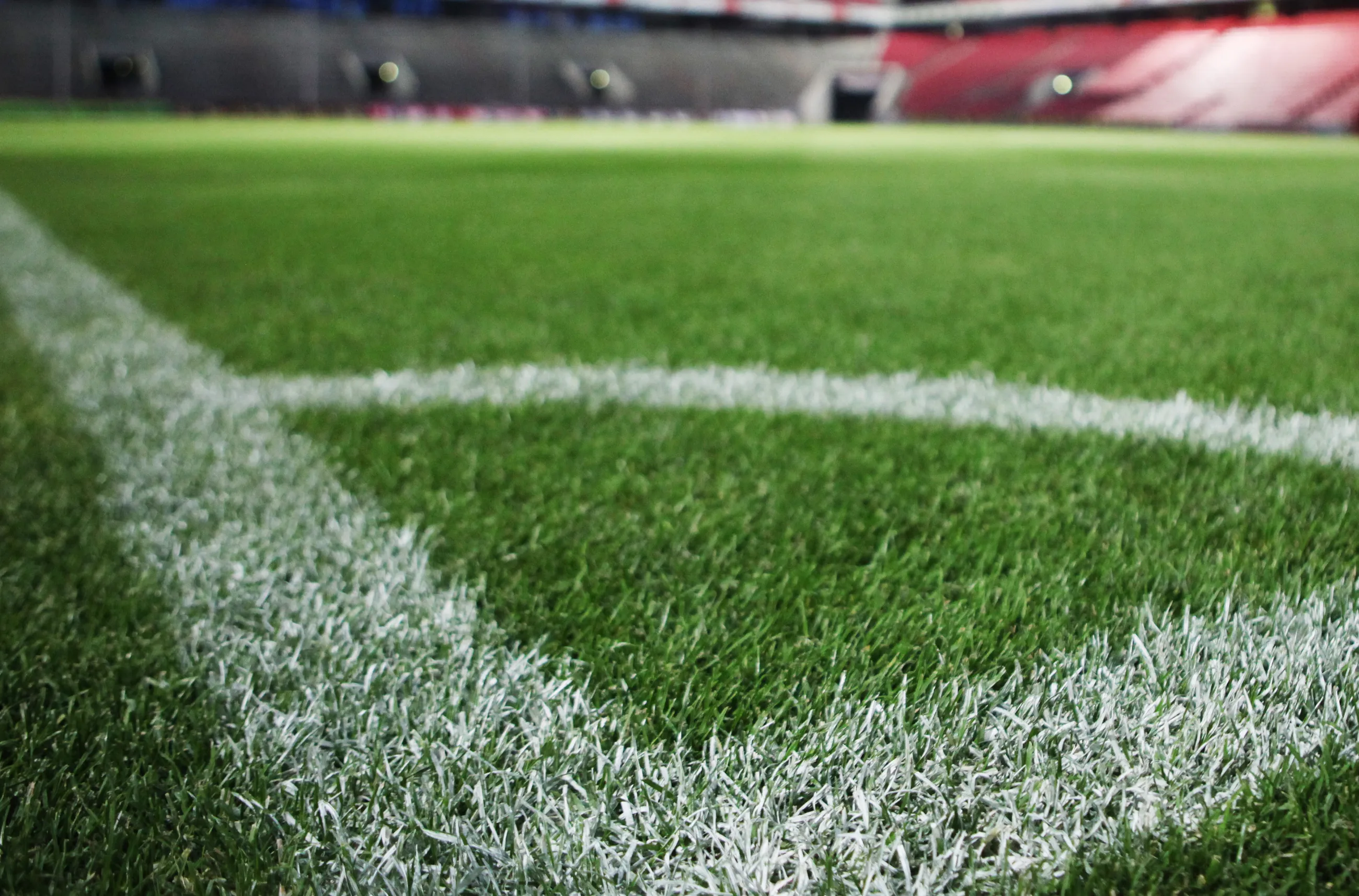 Symbolbild Fußballplatz, Nahaufnahme des Rasens mit weißen Linien