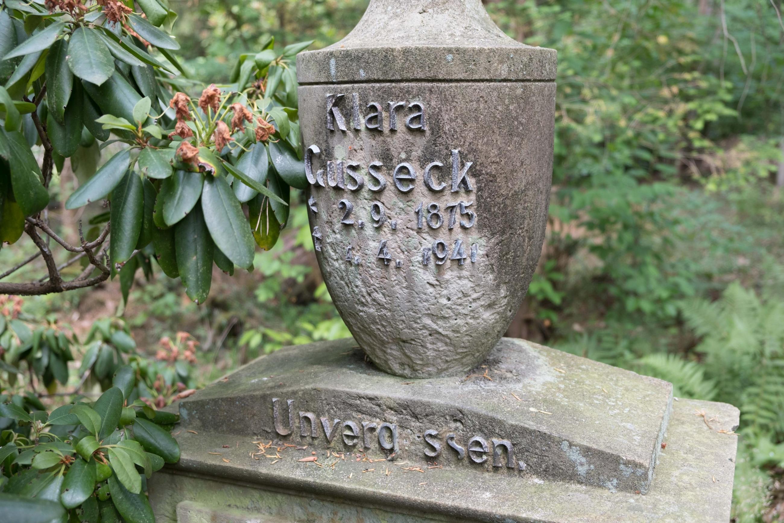 Grabmal von Clara Gusseck mit einer Aufschrift aus kupfernen Lettern. Die Aufschrift umfasst ihren Namen, Geburts- und Sterbedatum und den Zusatz "unvergessen". Clara Gusseck lebte von 1875 bis 1941.