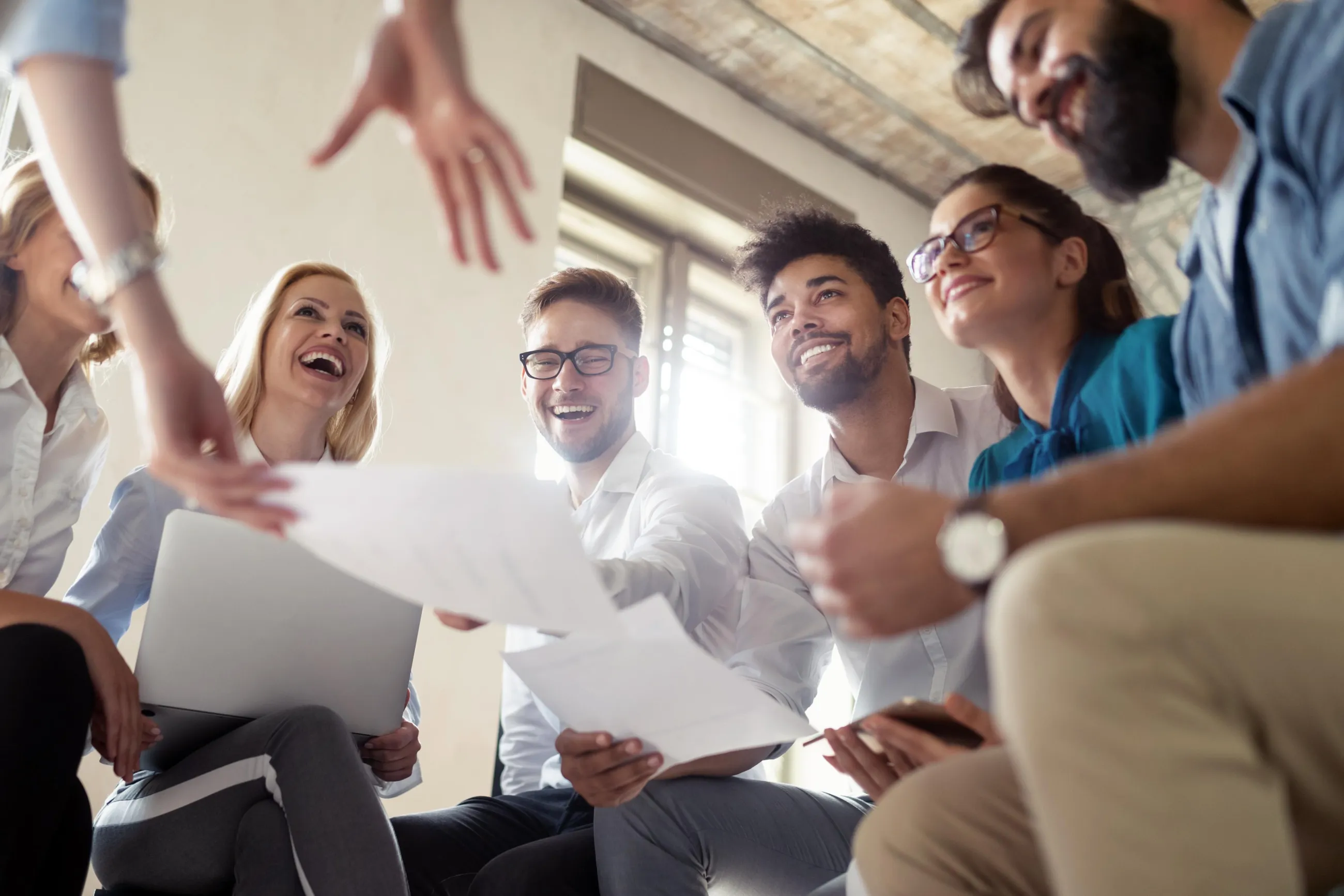 Studierende sitzen in einem Kreis in Arbeitsatmosphäre und lachen