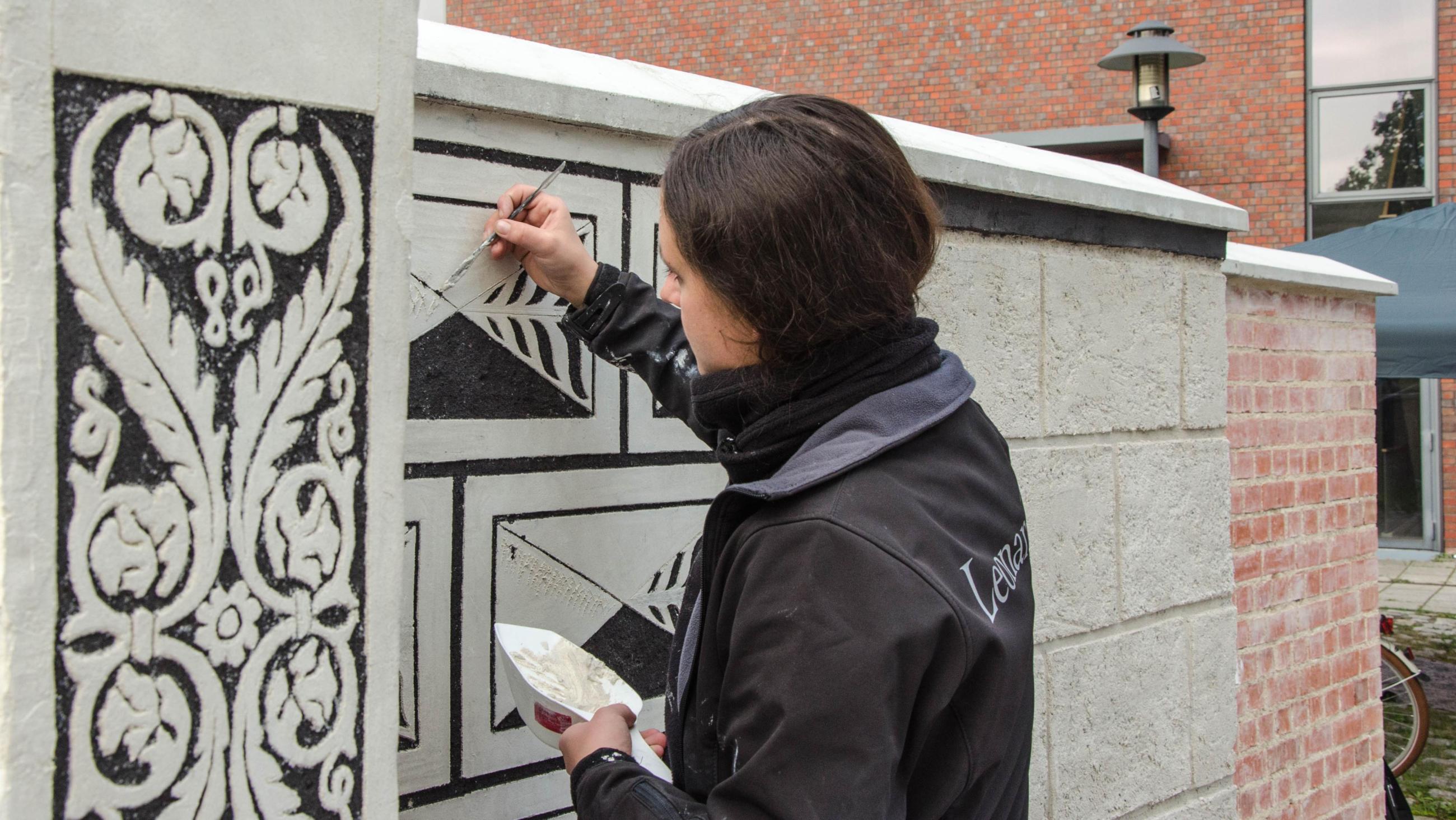 Studentin übt Malereitechniken an Außermauer auf dem Campus der FH Potsdam