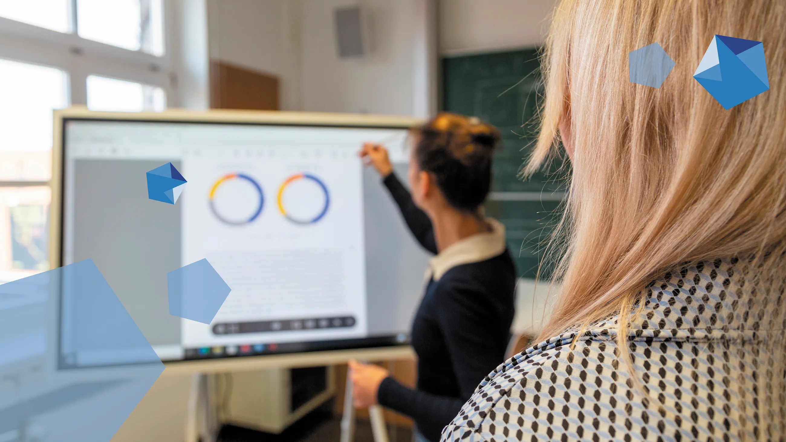 Zwei Frauen schauen auf Monitor mit abgebildeter Statistik