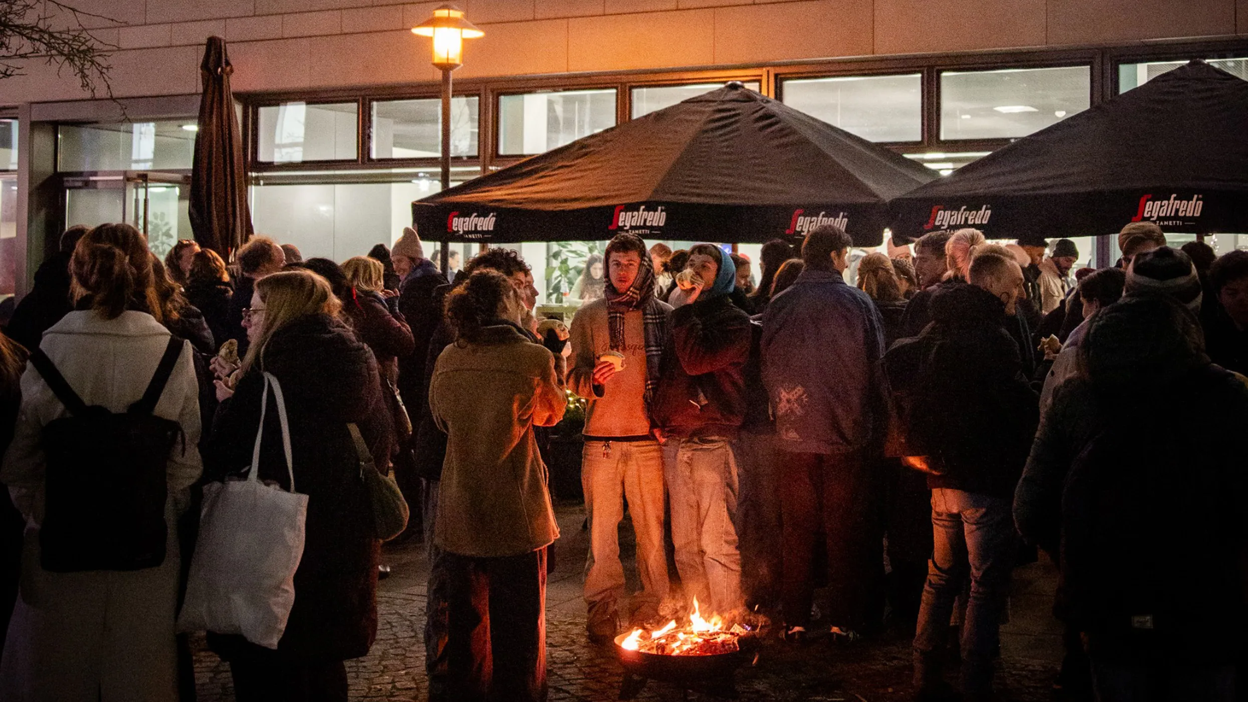 Menschen vor einem Lagerfeuer auf dem Campus der FH Potsdam