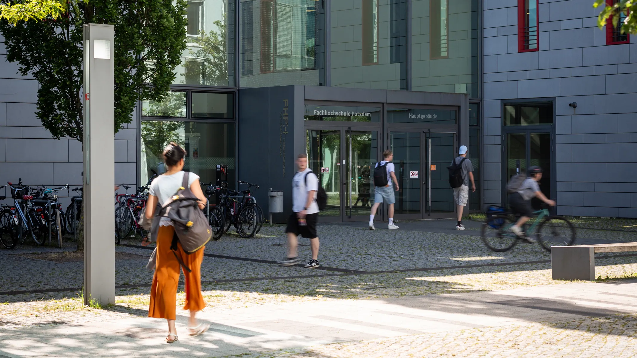 Studierende und Mitarbeitenden kommen zu Fuß am Hauptgebäude an