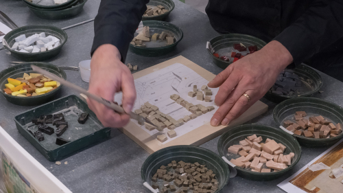 Eine Person setzt Mosaiksteine in einer Werkstatt der Konservierung und Restaurierung