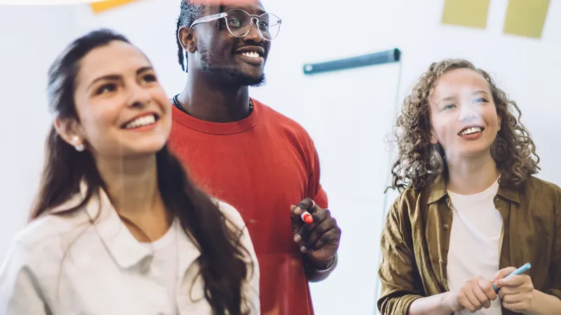Lachende Mitarbeitende schauen auf Klebezettel