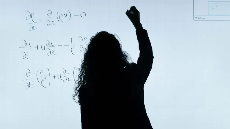Eine Professorin schreibt etwas an ein Whiteboard