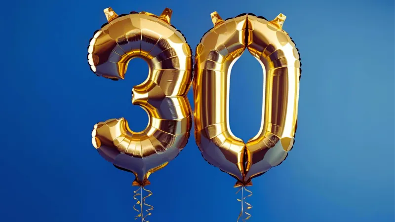 Goldene Ballons von drei und null vor blauem Hintergrund