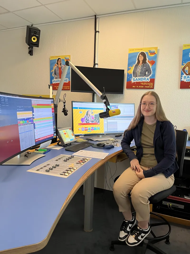 Johanna sitzt im Aufnahmestudio vor Bildschirm und Mikro