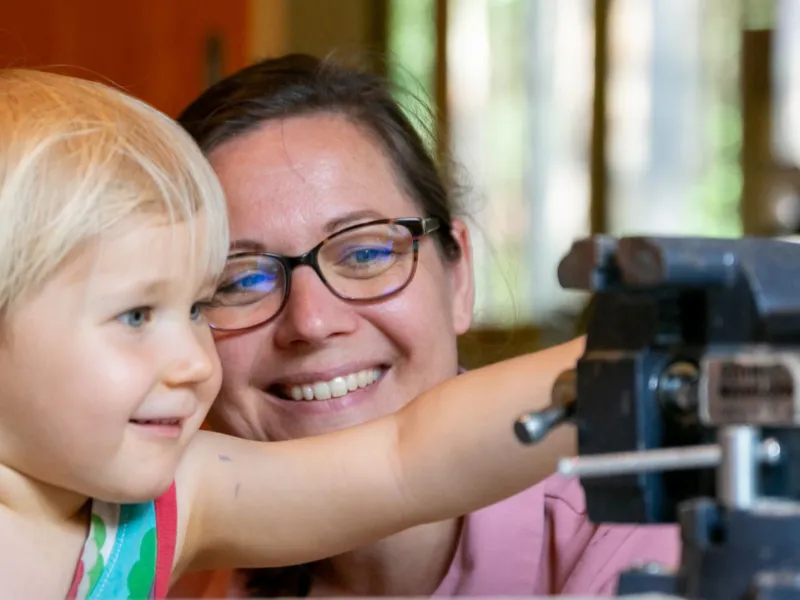 Prof. Dr. Gerlind Große mit einem Kleinkind an einer Werkbank
