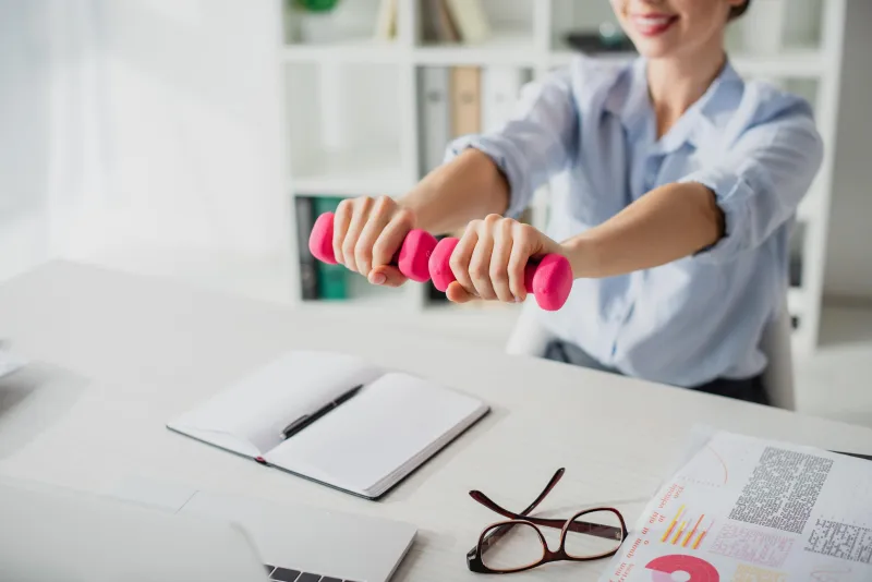 Mitarbeitende führt Kurhantel-Übungen am Schreibtisch aus