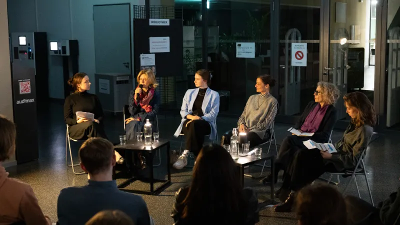 Das Publikum hört mehreren Frauen im Foyer der Bibliothek zu