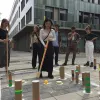 Teilnehmende spielen auf Asphaltboden ein dem Cricket ähnliches Spiel